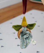 The Nanchen green Flower Fairy Ring Grasper shown suspended from a piece of red velvet ribbon. 