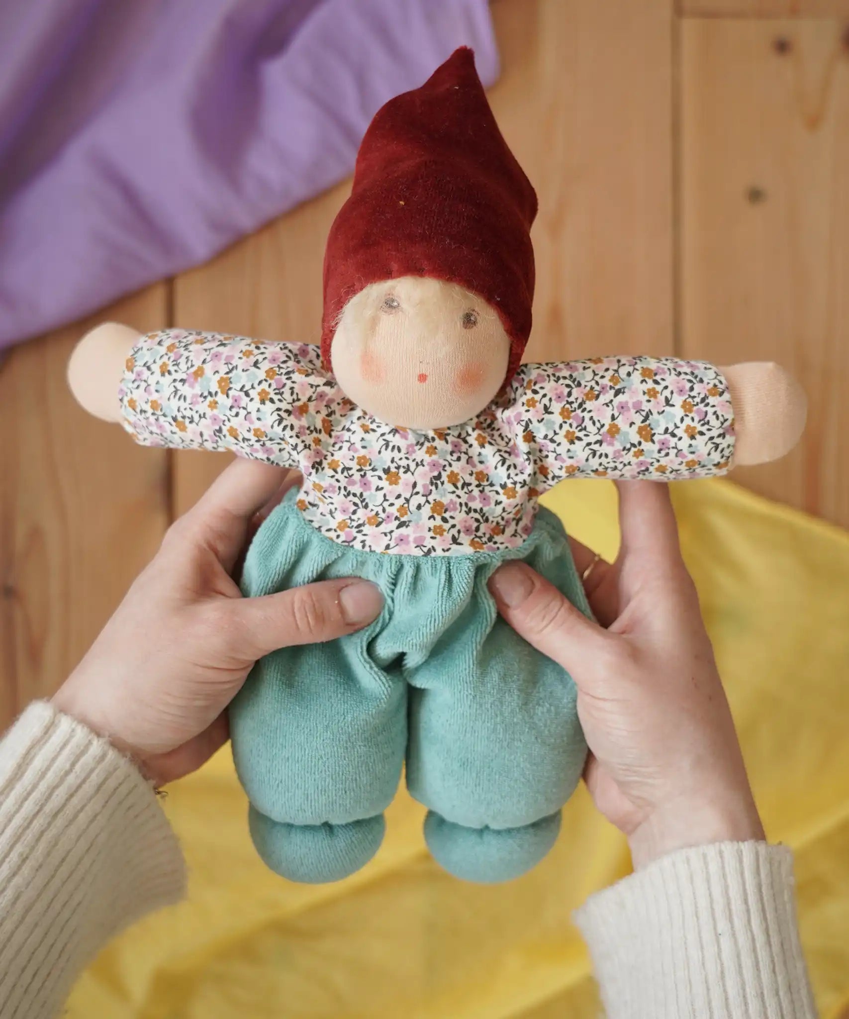 Nanchen mint forest child Waldorf doll in an adult's hands in the Babipur playroom.