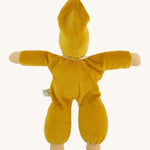 The back of the Nanchen Waldorf Nani Doll. This hand crafted doll toy has a gold fabric, soft body with a small white collar and gold pointy hat. On a cream background