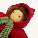 A close up of the  Nanchen handcrafted Little Red Riding Hood Waldorf doll#f face with the clothing on and the hood of the coat up.