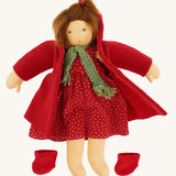 The Nanchen handcrafted Little Red Riding Hood Waldorf doll shown with the red coat opened revealing the spotty cord dress underneath. The doll's shoes have been removed and placed besides her.