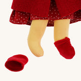 A close up of the  Nanchen handcrafted Little Red Riding Hood Waldorf doll's feet. The doll has one red coloured velvet slipper type shoe on and one off. 