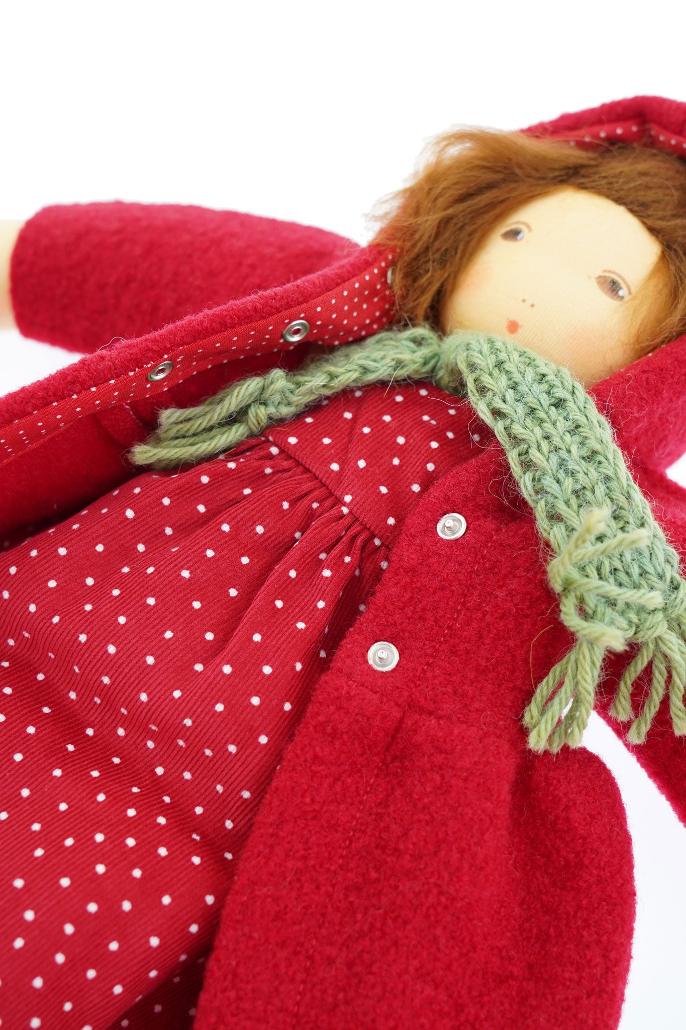 A close up of the popper closure on the  Nanchen handcrafted Little Red Riding Hood Waldorf doll's red coloured coat.