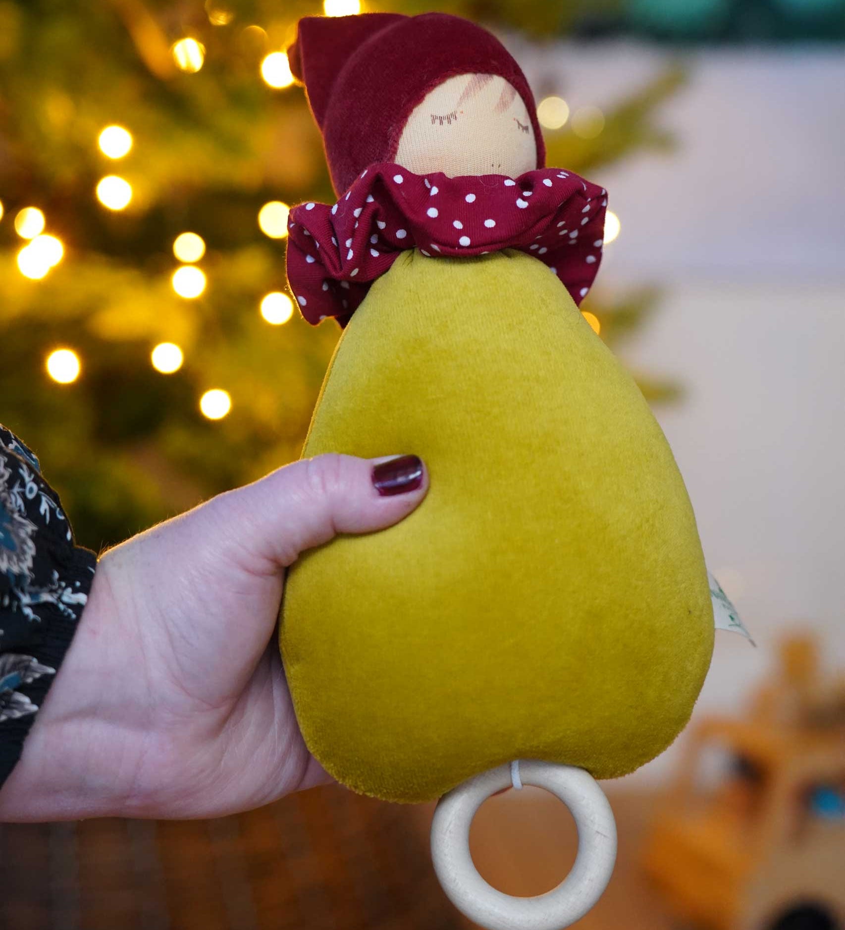 A close up of the Nanchen Little Red Riding Hood Lullaby Music Doll in an adult's hand. A musical Waldorf doll, made from organic cotton and sheep's wool. 