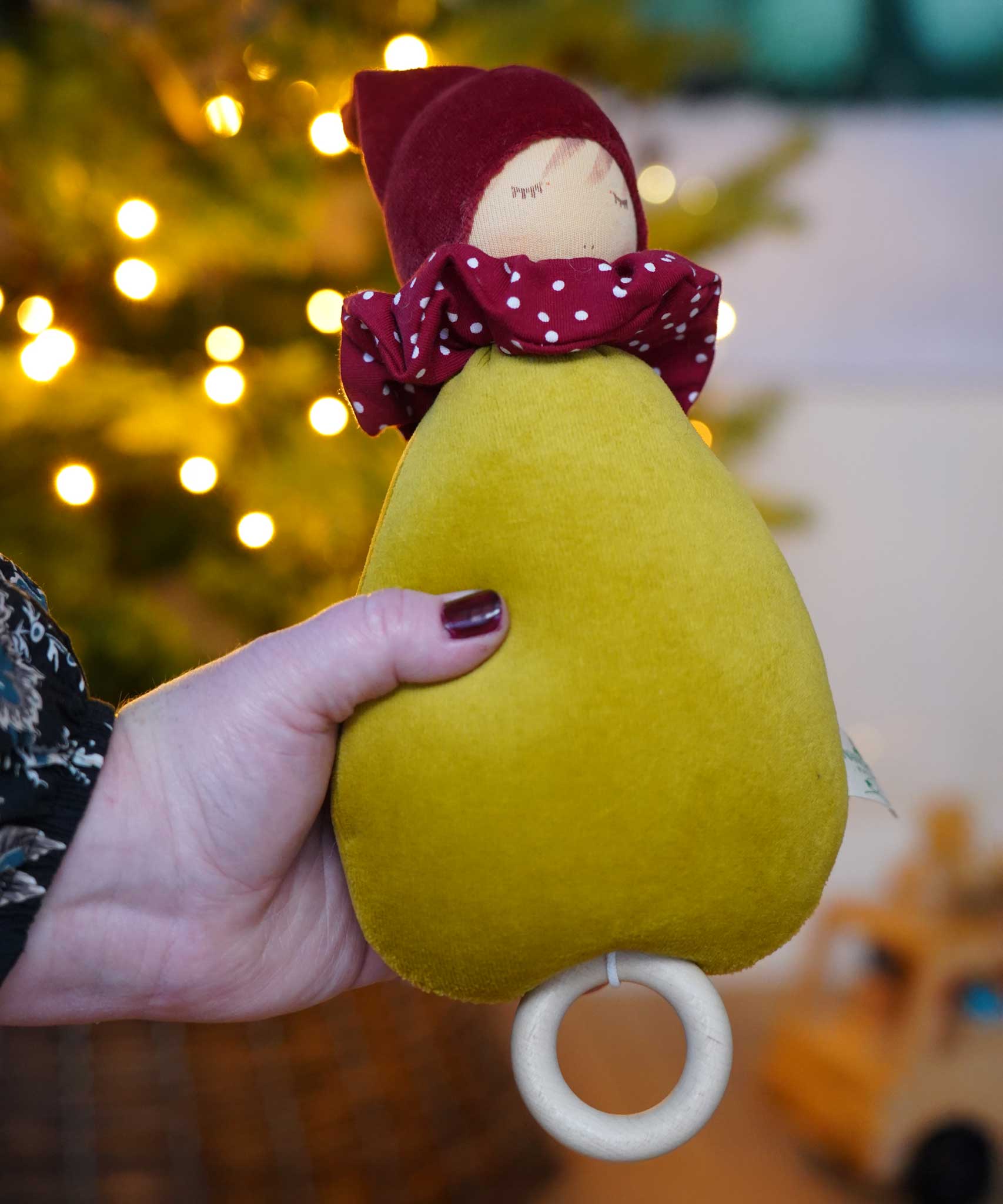 A close up of the Nanchen Little Red Riding Hood Lullaby Music Doll in an adult's hand. A musical Waldorf doll, made from organic cotton and sheep's wool. 