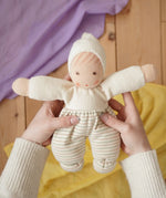 Nanchen Möpschen Waldorf doll in natural white colour with striped pattern on trousers in an adult's hand in the Babipur playroom.
