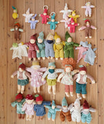 Large selection of Nanchen Natur handmade organic Waldorf dolls and comforters placed on a wooden floor in the Babipur playroom.