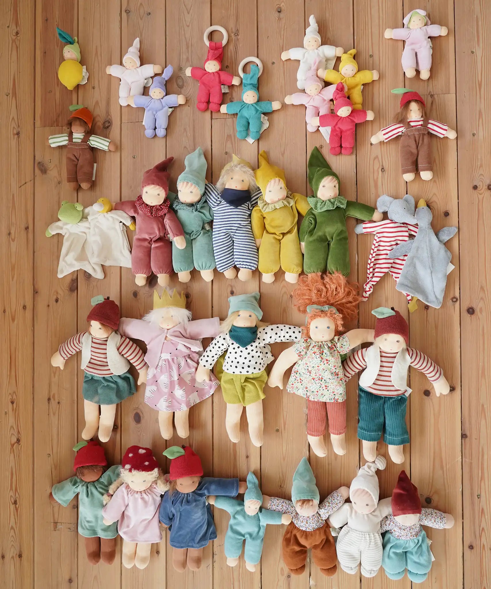 Large selection of Nanchen Natur handmade organic Waldorf dolls and comforters placed on a wooden floor in the Babipur playroom.