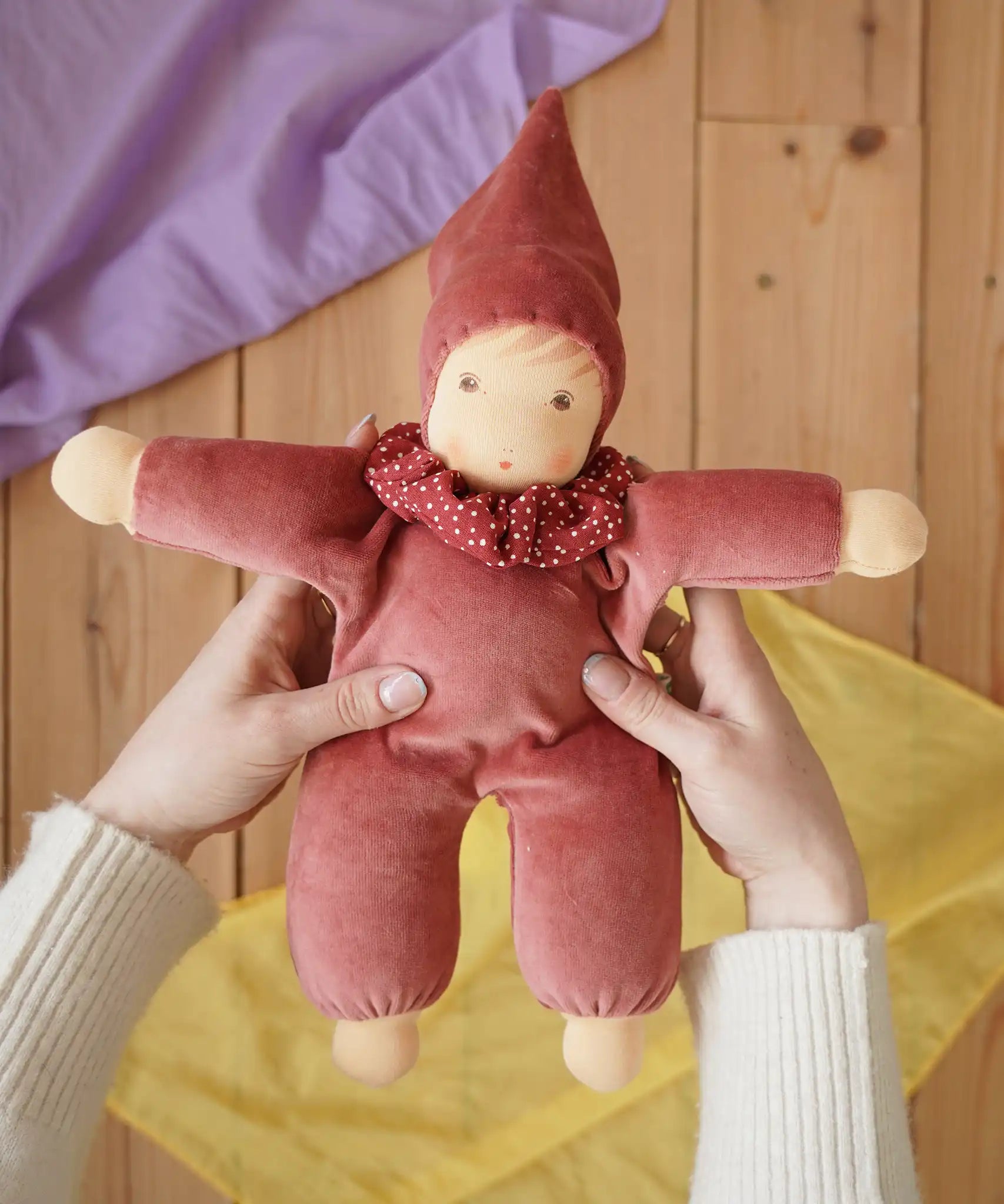 Nanchen Natur Nani Waldorf doll in cedar pink in an adult's hands in the Babipur playroom. 