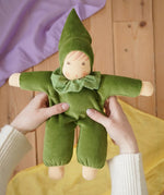 Nanchen Natur Waldorf Nani doll in forest green in an adult's hands in the Babipur playroom. 