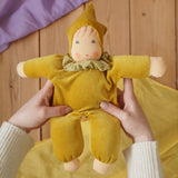 Nanchen Natur Nani Waldorf doll in gold in an adult's hand in the Babipur playroom. 