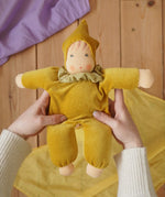 Nanchen Natur Nani Waldorf doll in gold in an adult's hand in the Babipur playroom. 