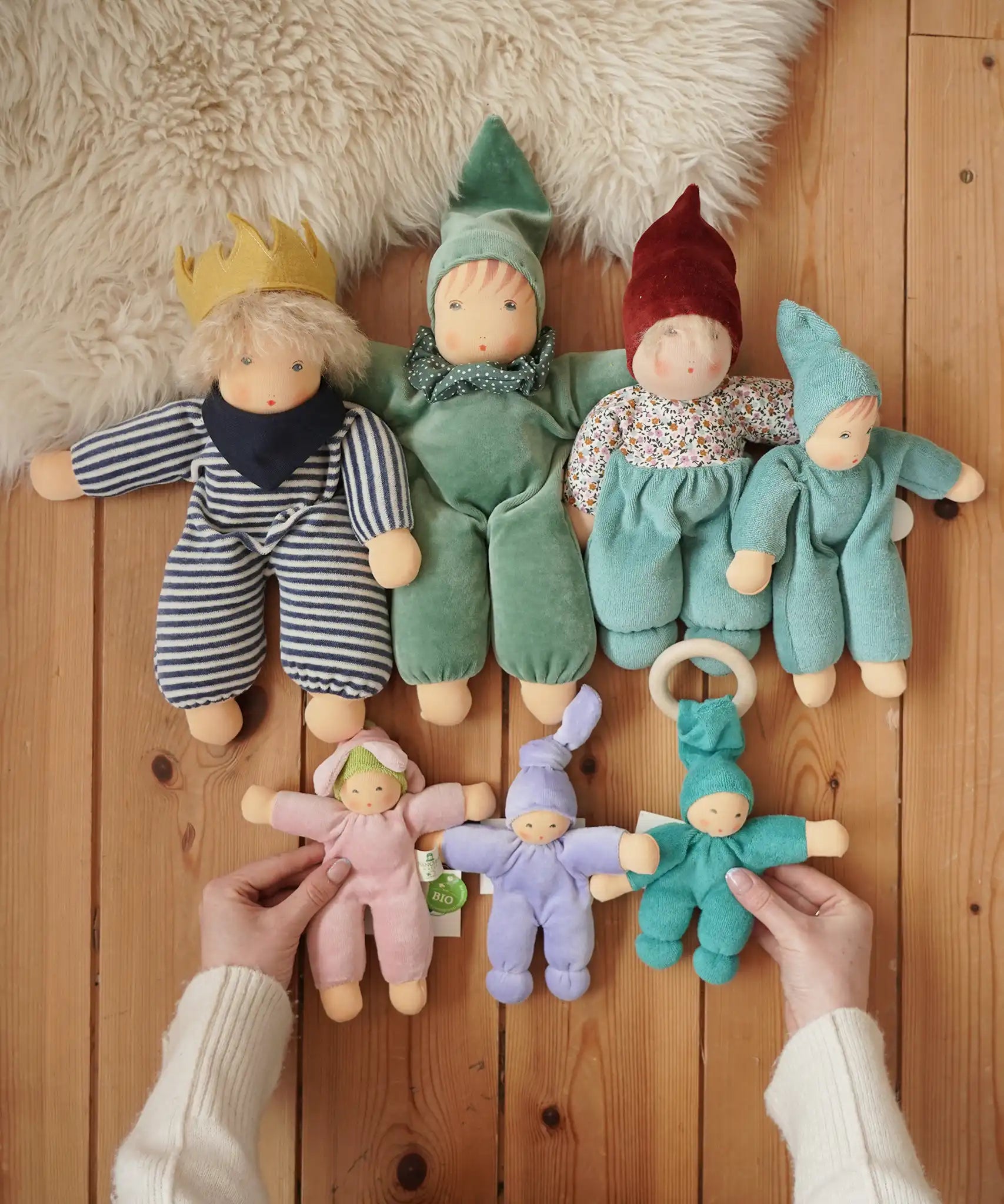 Collection of Nanchen Natur handmade Waldorf dolls placed on a wooden floor in the Babipur playroom. 