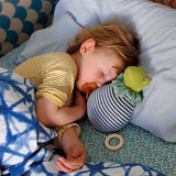 A child having a nap next to his Nanchen Natur 'Brave Little Frog' musical Waldorf doll, made from organic cotton and sheep's wool. 