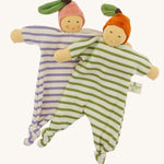 Front view of the Nanchen Orange and Peach Baby Comforters, showing their full striped cotton terry bodies with knotted feet and outstretched arms. Each wears a velour fruit-inspired hat with a green leaf, one in orange and the other in pink.