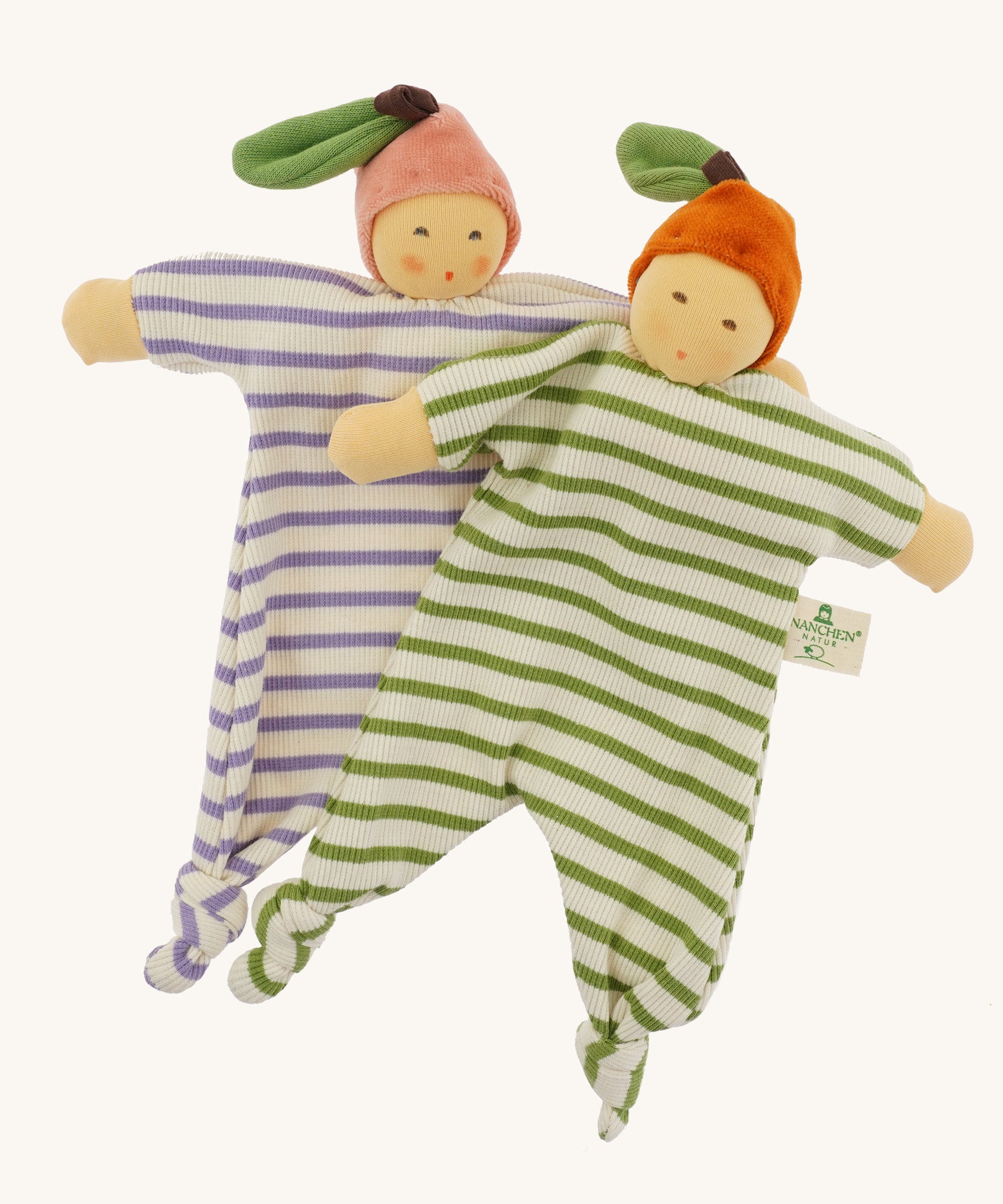 Front view of the Nanchen Orange and Peach Baby Comforters, showing their full striped cotton terry bodies with knotted feet and outstretched arms. Each wears a velour fruit-inspired hat with a green leaf, one in orange and the other in pink.