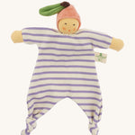 Front view of the Nanchen Peach Baby Comforter, a handmade doll with a soft, peach-colored face and pink velour fruit-shaped hat with a green leaf and brown stem. The doll has a lilac and white striped organic cotton terry body with knotted feet and outstretched arms, and a fabric label reading "Nanchen Natur" on the side.