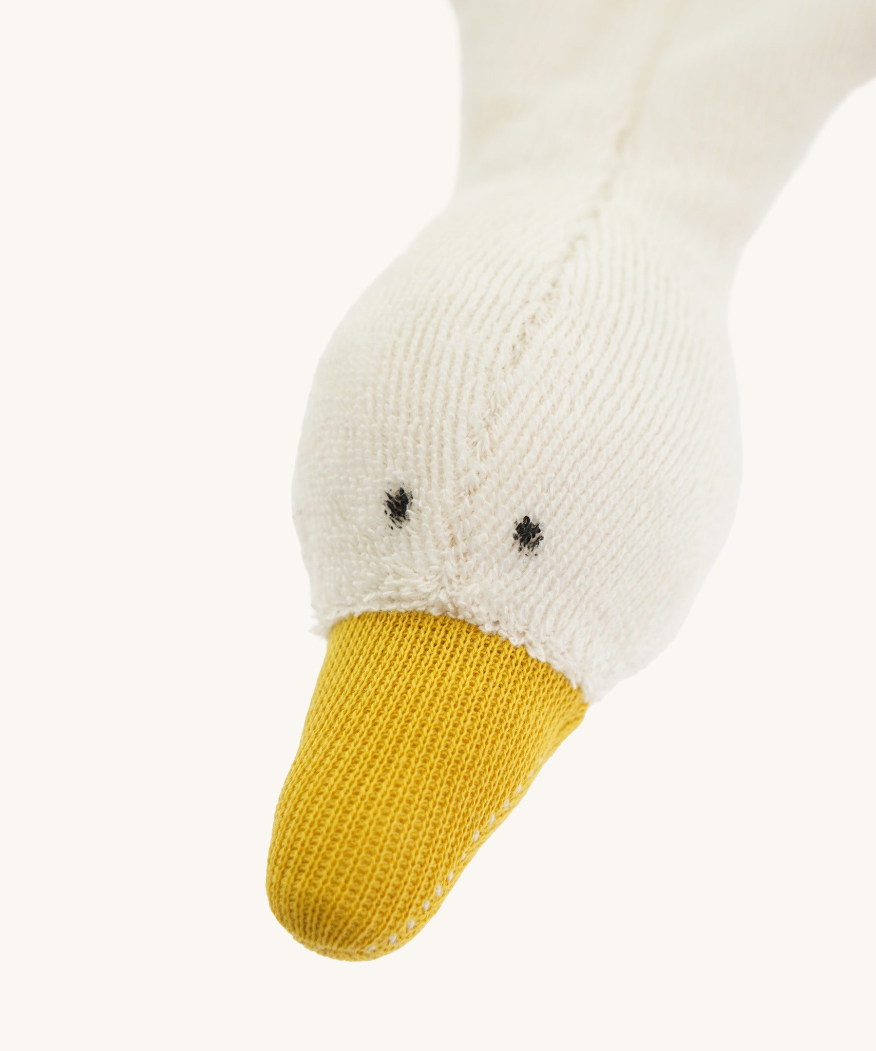 Close-up of the goose’s head on the Nanchen Baby Comforter, showing hand-stitched black eyes, soft terry fabric, and a mustard yellow beak. The wool-stuffed head contrasts with the flat, unstuffed body.