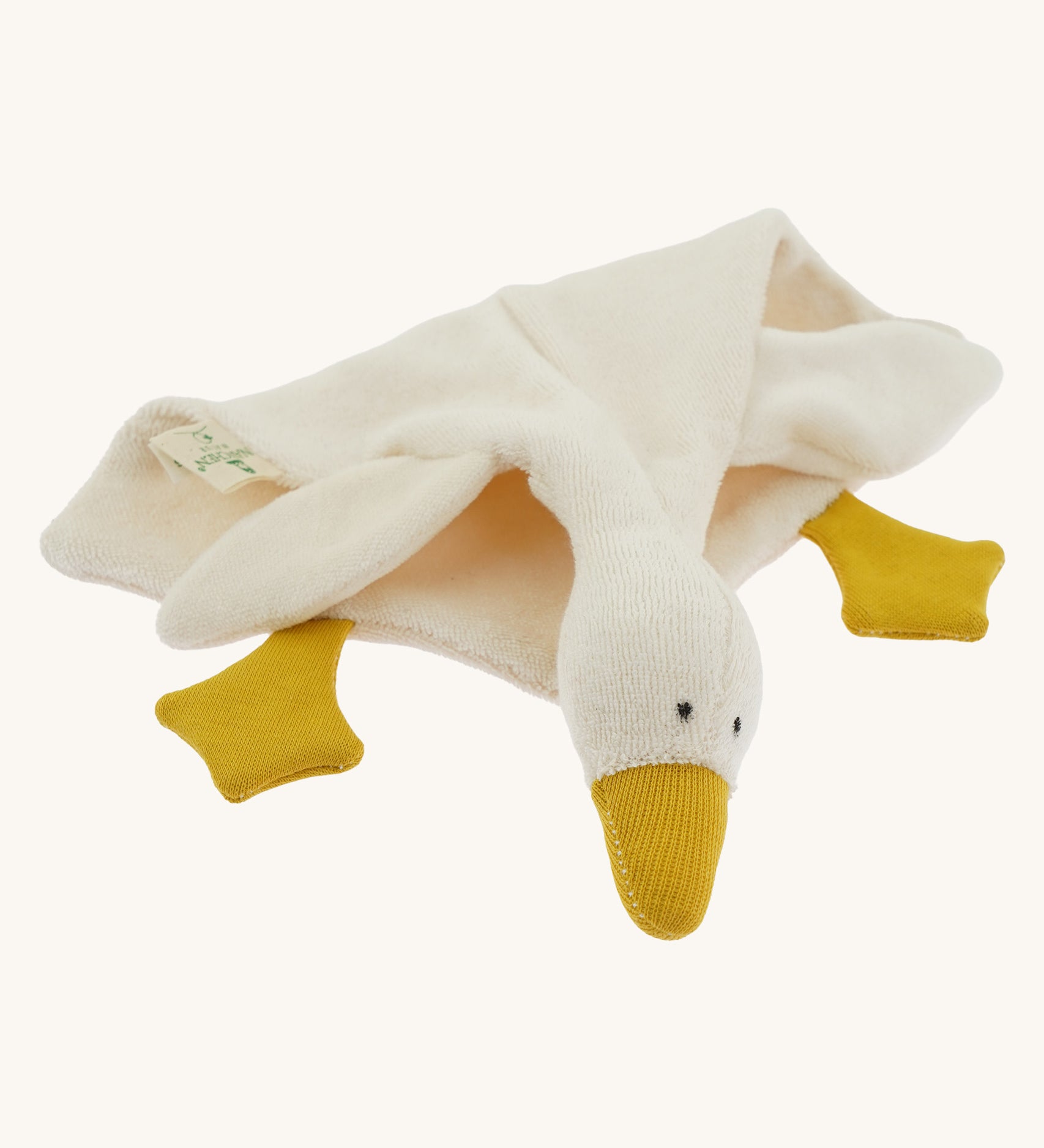 Side view of the Nanchen White Goose Comforter lying down. The doll’s soft terry fabric body drapes naturally, highlighting its cuddly, blanket-like shape and plush wool-stuffed head.