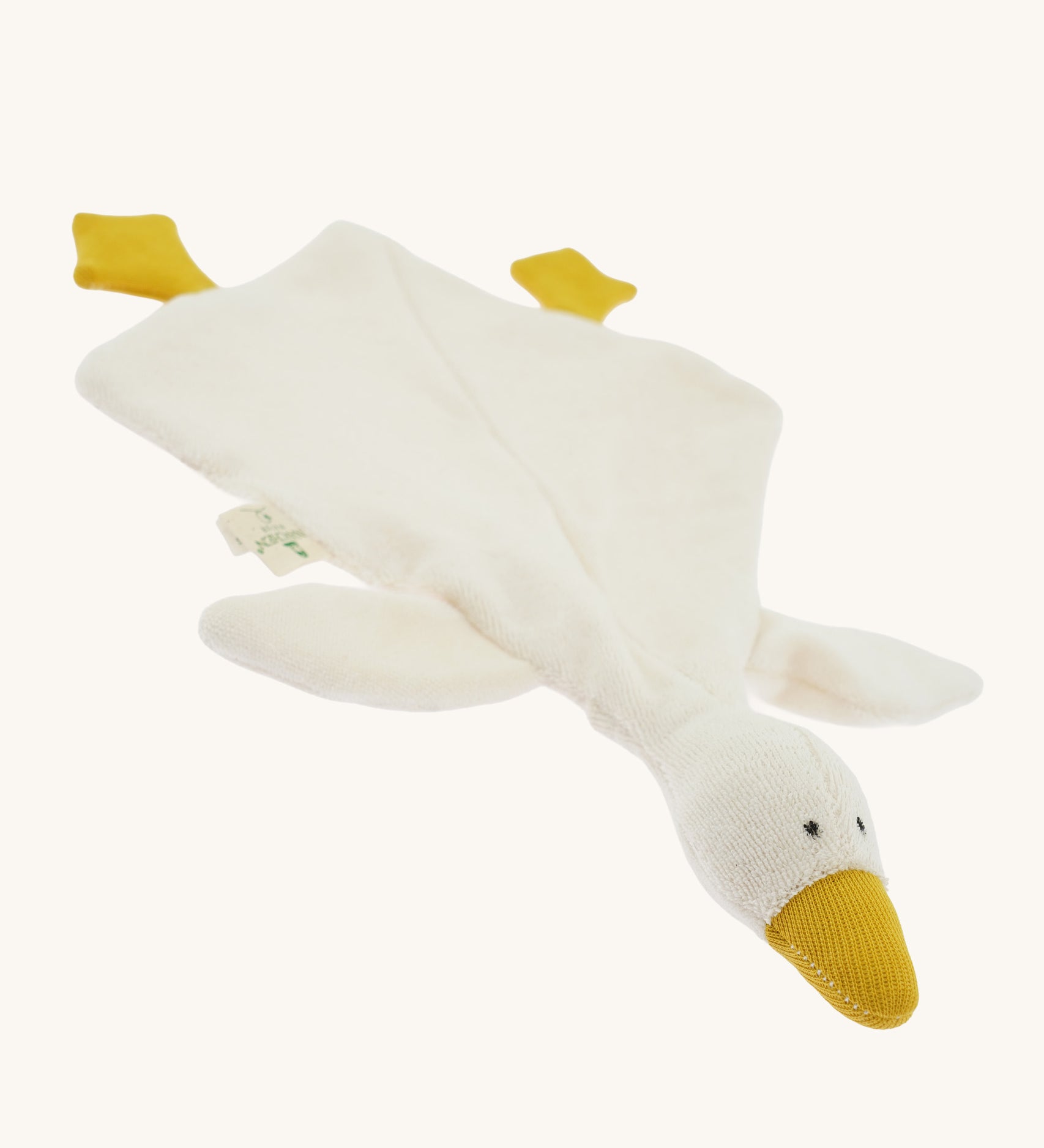 Angled front view of the Nanchen White Goose Baby Comforter laid flat. The soft cream-colored blanket body spreads out with attached yellow feet and a raised plush goose head with a gentle, minimalist expression.
