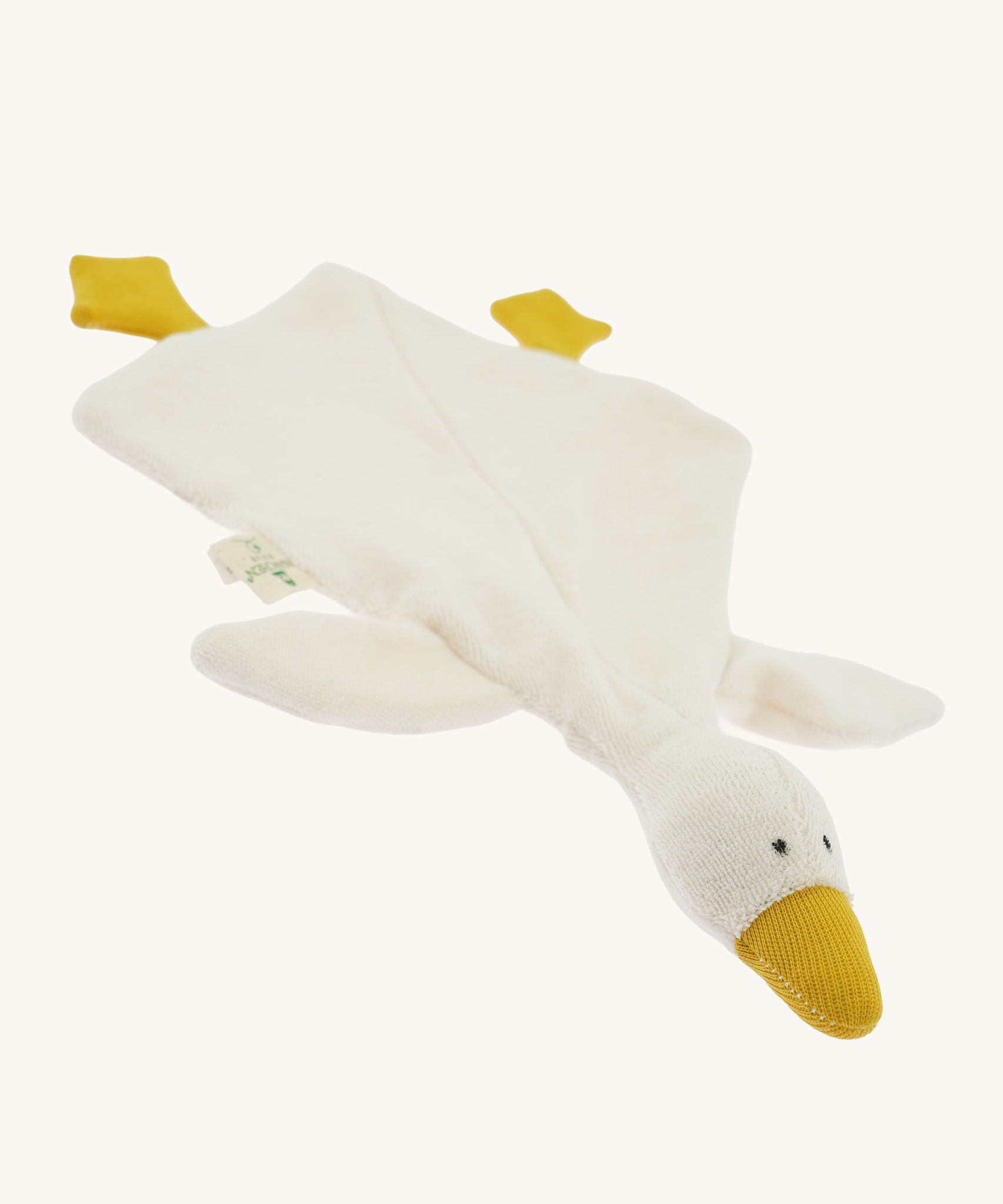Angled front view of the Nanchen White Goose Baby Comforter laid flat. The soft cream-colored blanket body spreads out with attached yellow feet and a raised plush goose head with a gentle, minimalist expression.