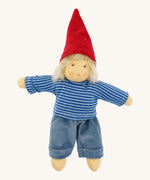Front-facing image of the Nanchen Frederik handmade Waldorf doll fully dressed in its gnome-inspired outfit, wearing a red pointed hat, blue striped top, and blue trousers. The doll has soft blond mohair hair and a natural peach-toned cotton body.