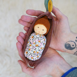 Nanchen Oak Baby Waldorf Doll - Floral. A little organic grasping doll in a brown velvet cradle in a persons hands.