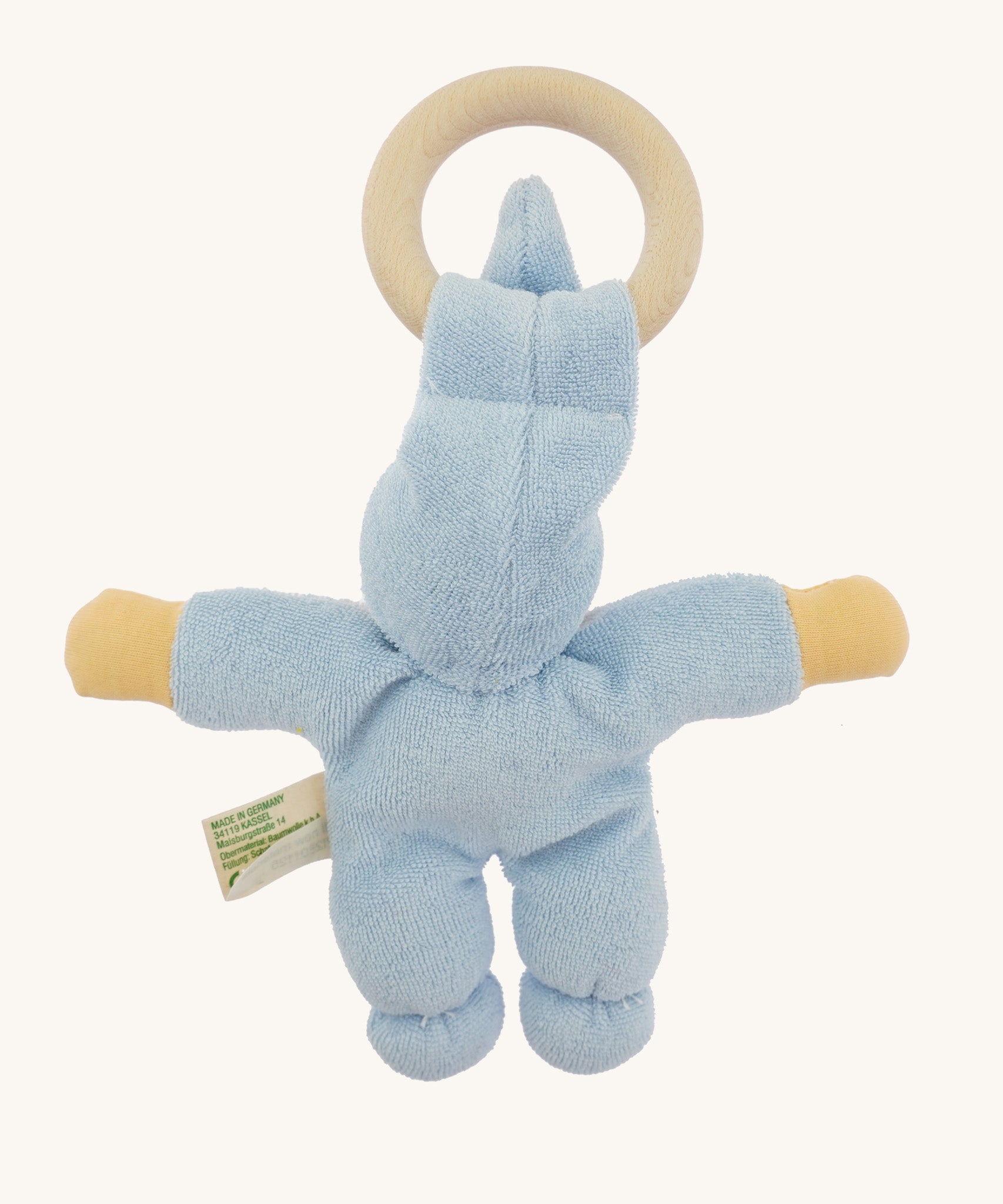Back view of the blue Nanchen Pimpel Doll, showing the full cotton terry body with plump limbs and the wooden teething ring held through the tall soft hat.
