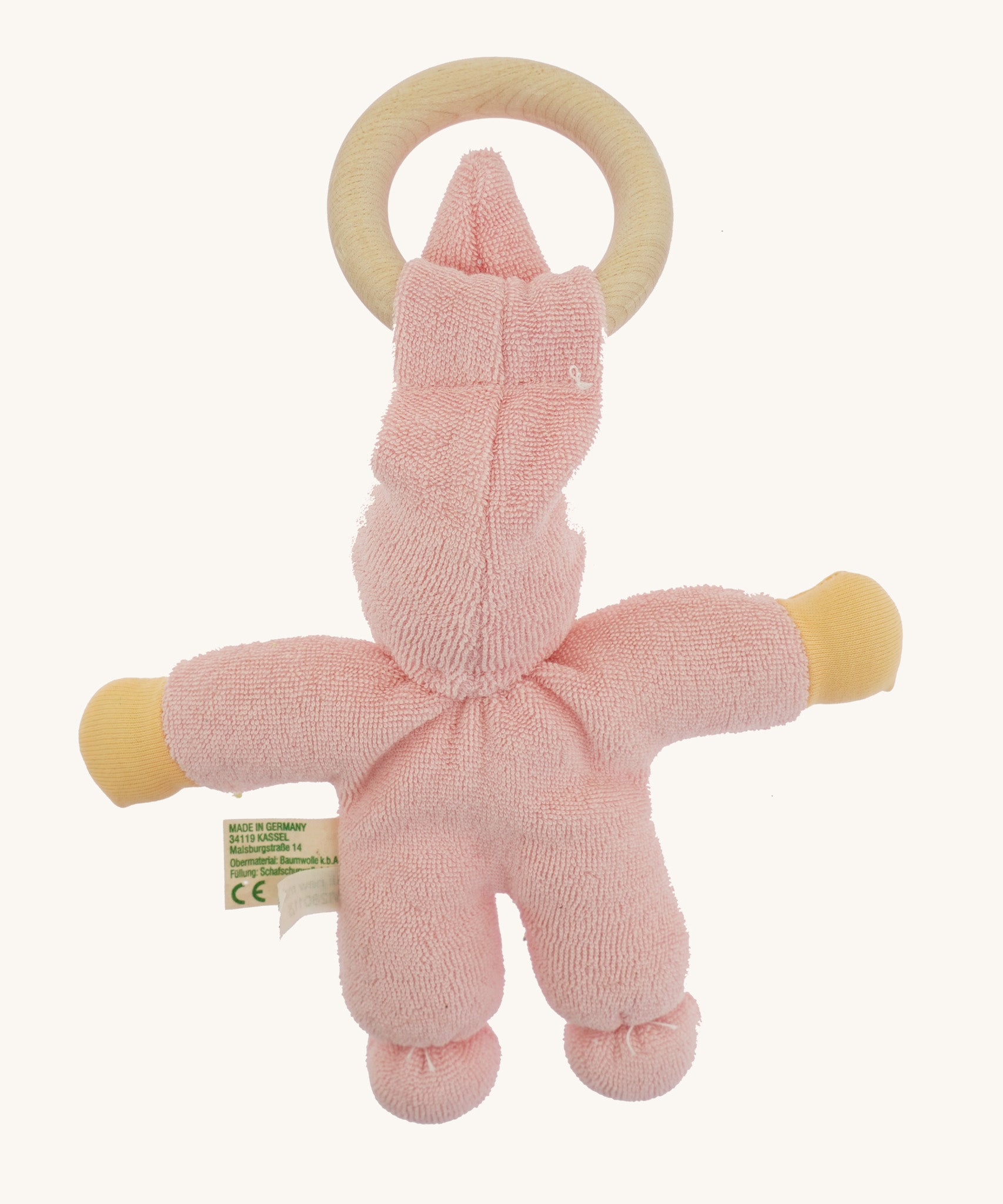 Back view of the pink Nanchen Pimpel Doll showing the soft texture of the organic cotton terry fabric, knotted feet, and the wooden teething ring looped through the pointed hat.