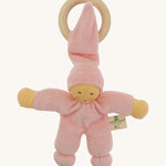 Front view of the Nanchen Pimpel Doll Baby Comforter in pink, with a pointed hat looped through a wooden teething ring. The doll has a natural-toned face with delicately painted features and soft yellow arms.