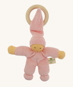 Front view of the Nanchen Pimpel Doll Baby Comforter in pink, with a pointed hat looped through a wooden teething ring. The doll has a natural-toned face with delicately painted features and soft yellow arms.
