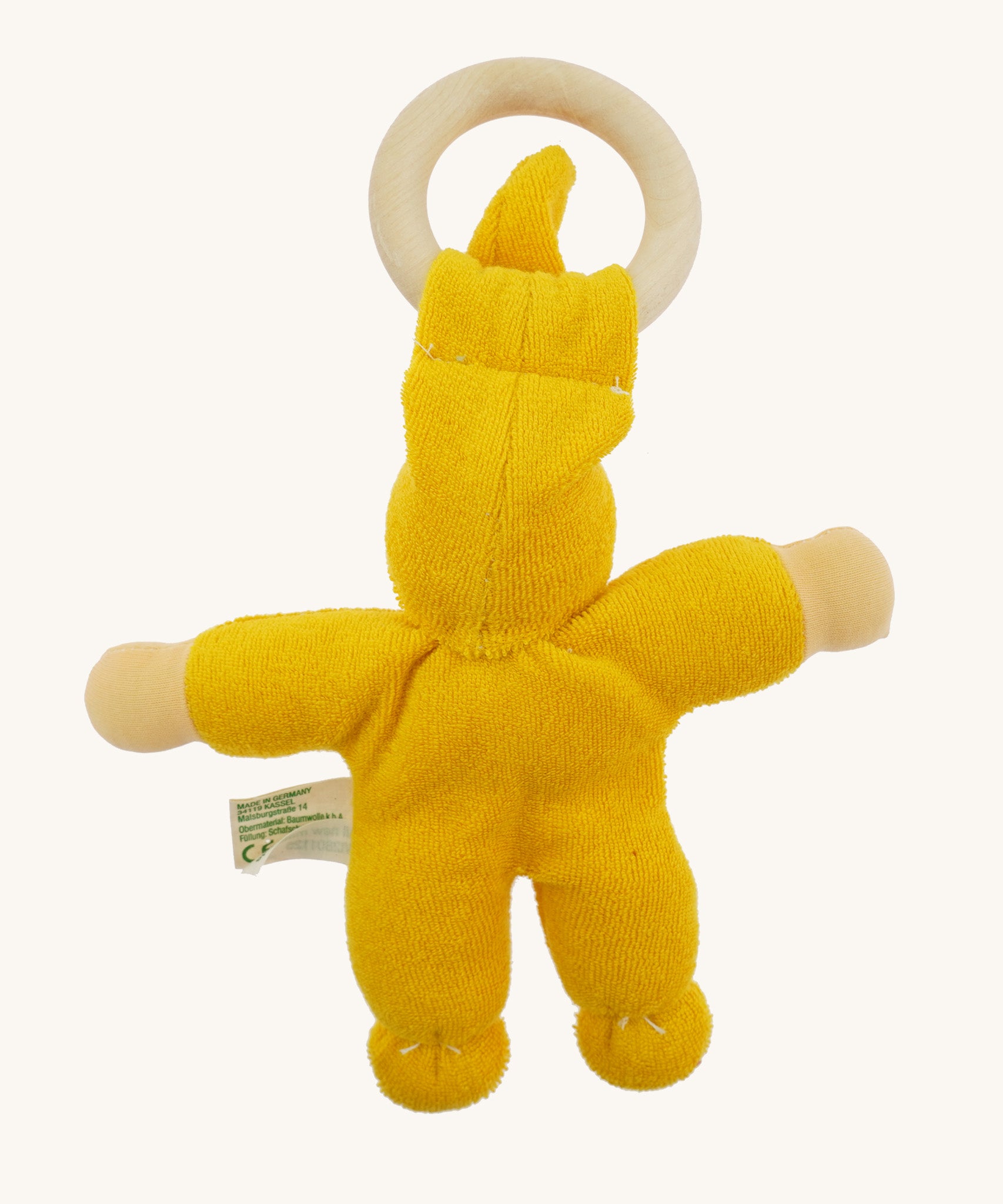 Back view of the yellow Nanchen Pimpel Doll, displaying the curved back stitching, rounded limbs, and how the wooden ring is held in place by the fabric hat.
