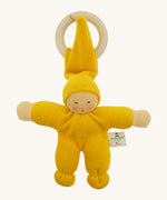 Front view of the Nanchen Pimpel Doll Baby Comforter in bright yellow, with a sweetly painted Waldorf-style face and wooden teething ring attached by its hat. The body and limbs are plush and rounded for cuddling.