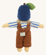 Back view of the Nanchen organic Waldorf doll named Bela Blueberry, dressed in a blue and white striped top, brown dungarees, and a soft blue fruit-style hat with a green leaf and brown stem. The doll has pale skin and fluffy blond hair peeking out from the hat.