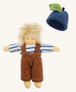 Nanchen organic Waldorf doll dressed in the blue and white striped top and brown dungarees, with the blueberry fruit hat beside it. The doll has pale skin and fluffy platinum blond hair.