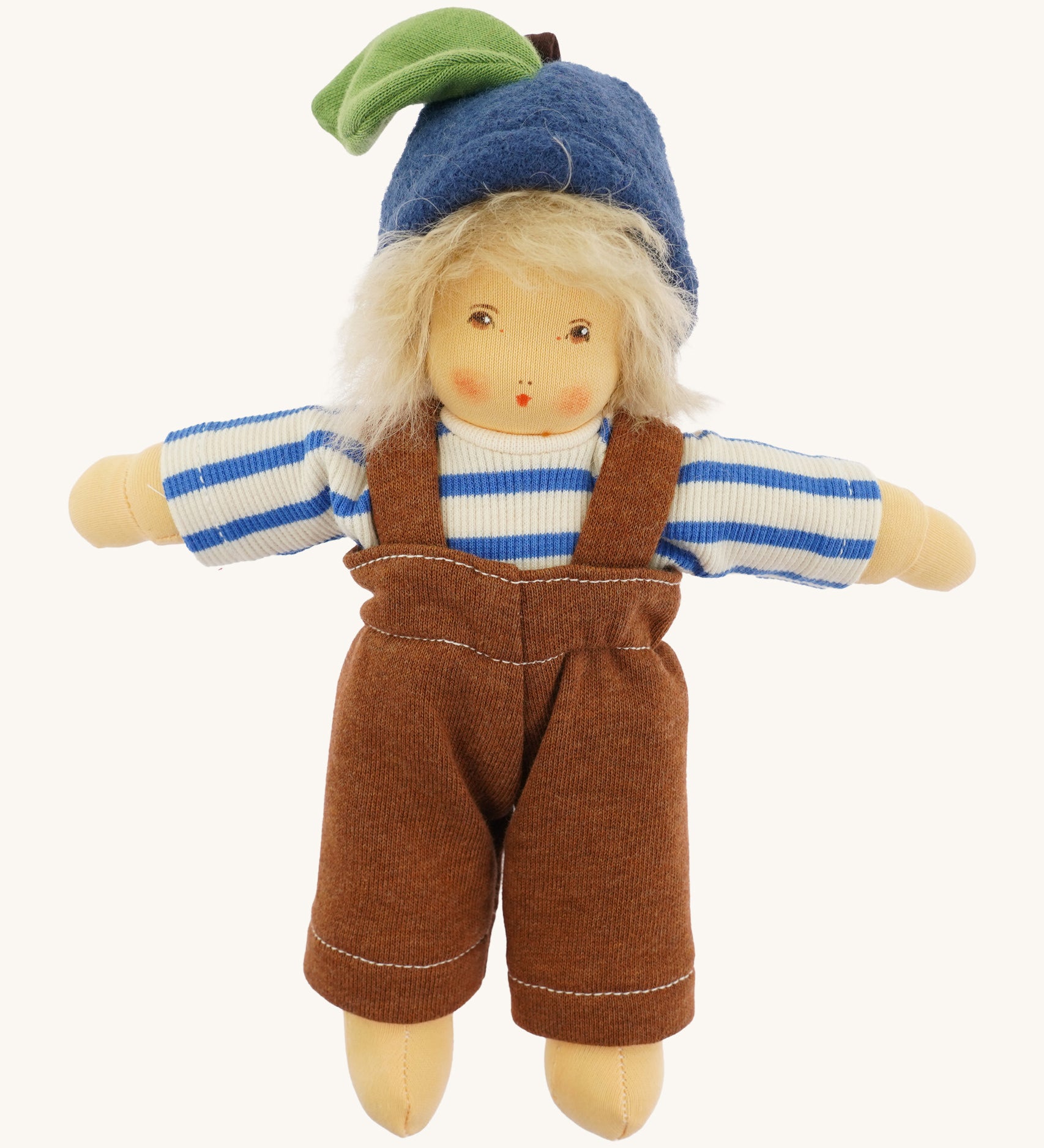 Front view of the Nanchen organic Waldorf doll Bela Blueberry, fully dressed in a blue and white striped long-sleeve top, brown dungarees, and a blue woollen fruit-style hat with a green leaf detail. The doll has soft blond hair and a gentle hand-painted expression.