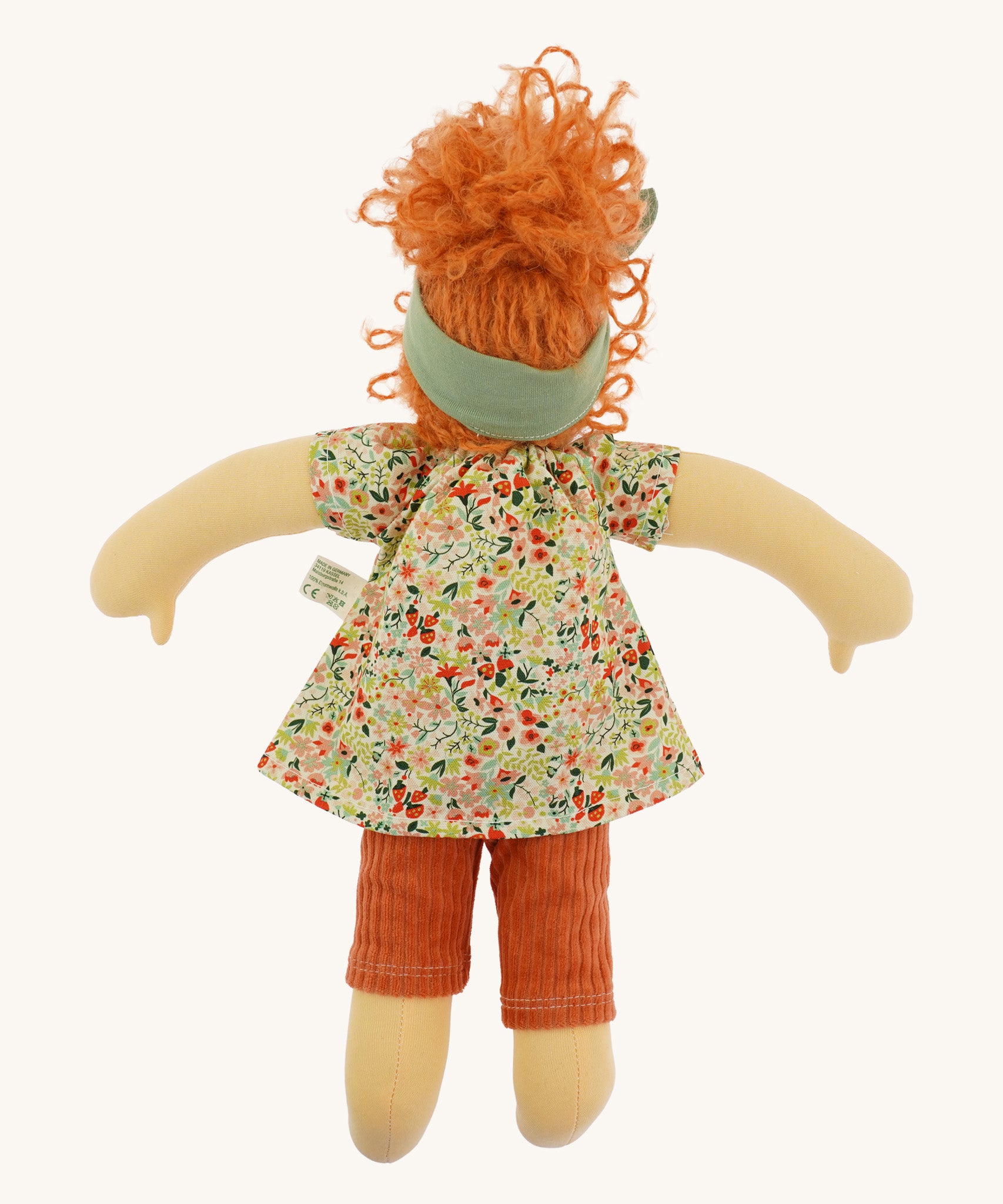 The back of The Nanchen 'Flore' organic Waldorf doll, with curly red hair, a floral top, orange trousers, and a green hair bow.