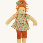 The Nanchen 'Flore' organic Waldorf doll, with curly red hair, a floral top, orange trousers, and a green hair bow.