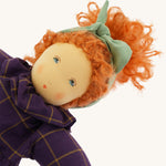 A closeup of the Nanchen 'Marlene' organic Waldorf doll, with curly red hair, a purple patterned dress, and blue eyes
