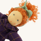A closeup of the Nanchen 'Marlene' organic Waldorf doll, with curly red hair, a purple patterned dress, and blue eyes