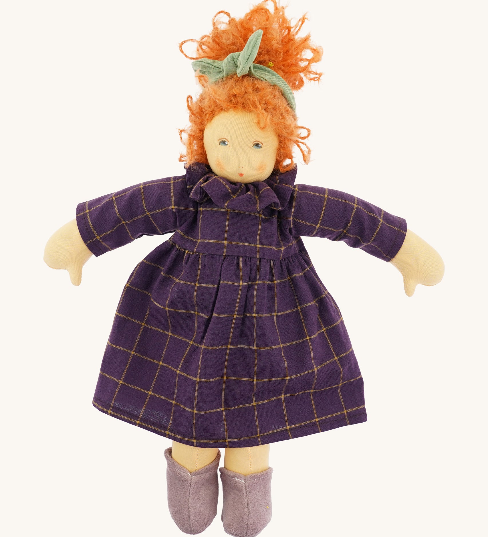 The Nanchen 'Marlene' organic Waldorf doll, with curly red hair, a purple patterned dress, lilac shoes, and a green hair bow.