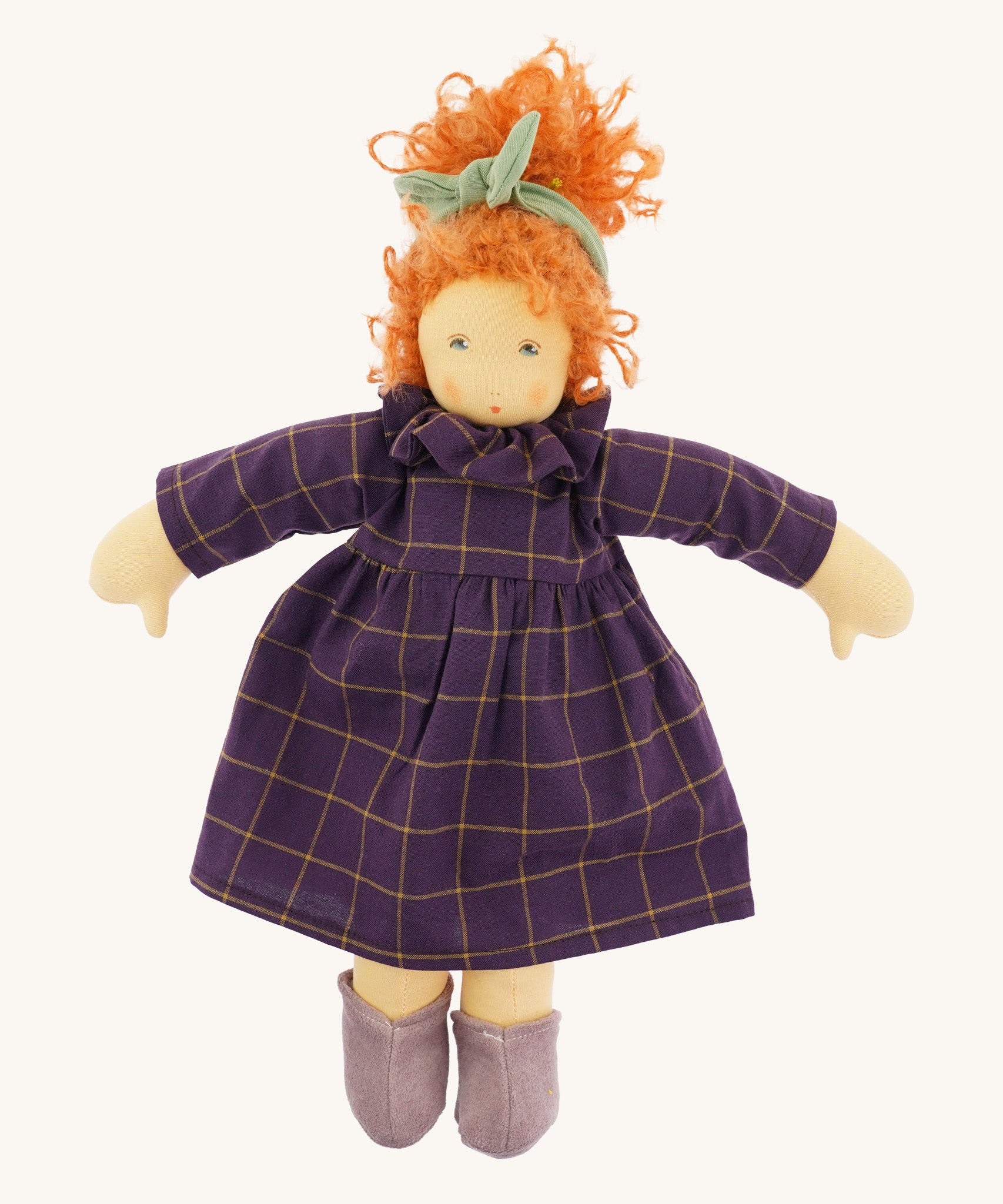 The Nanchen 'Marlene' organic Waldorf doll, with curly red hair, a purple patterned dress, lilac shoes, and a green hair bow.