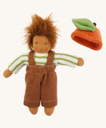 Nanchen organic Waldorf doll dressed in a green and white striped top and brown dungarees, with the orange fruit hat placed beside it. The doll has brown skin and fluffy brown hair.