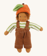 Front view of the dressed Nanchen organic Waldorf doll in green striped top, brown dungarees, and orange fruit hat with green leaf. The doll has brown skin and spiky brown hair.