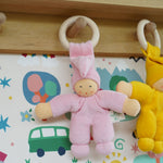 A Pink Nanchen Pimpel Waldorf Doll Ring Comforter hung up by it's wooden ring on a wooden peg on a shelf.