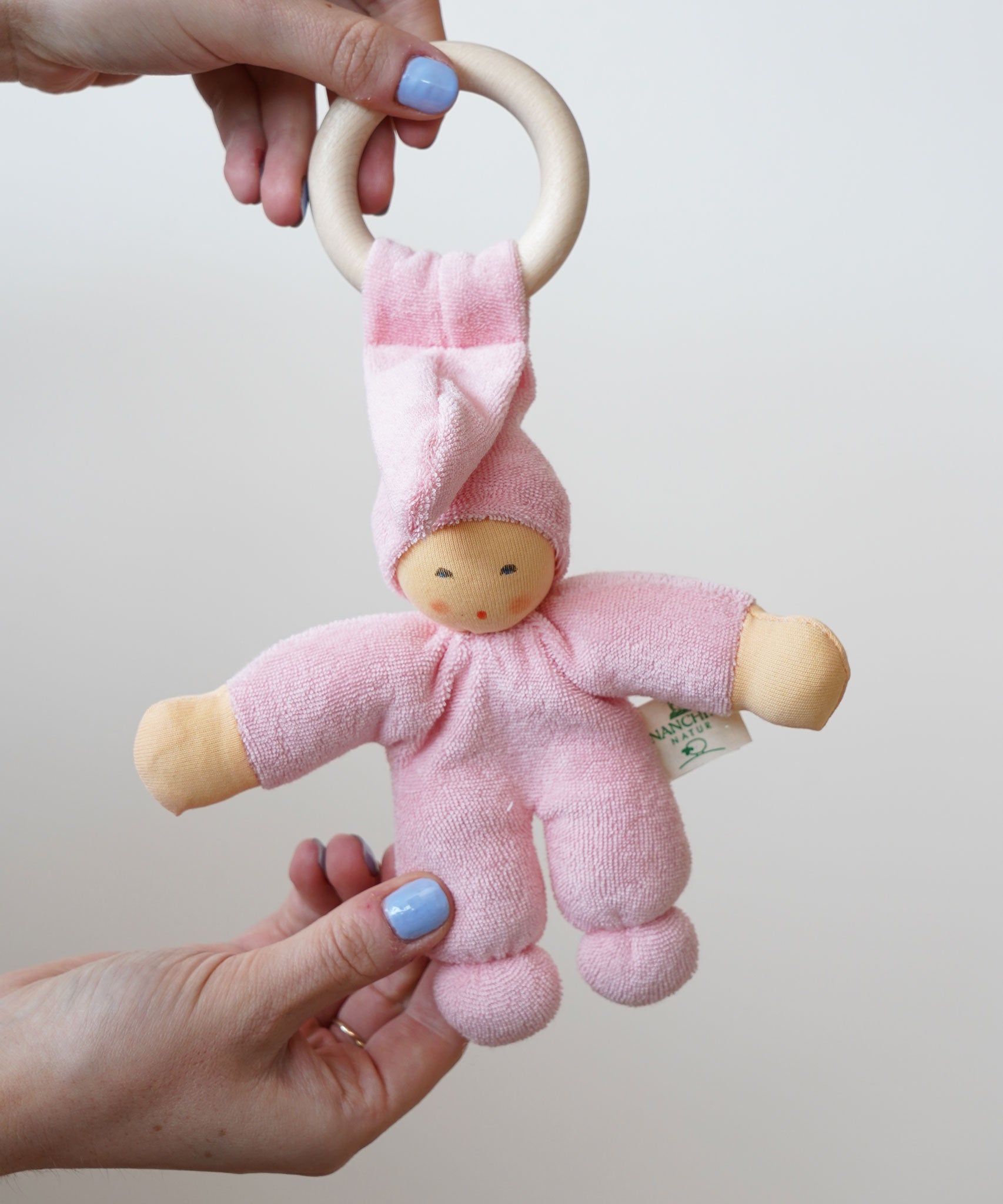A pink Nanchen Pimpel Waldorf Doll Ring Comforter in an adult's hands.
