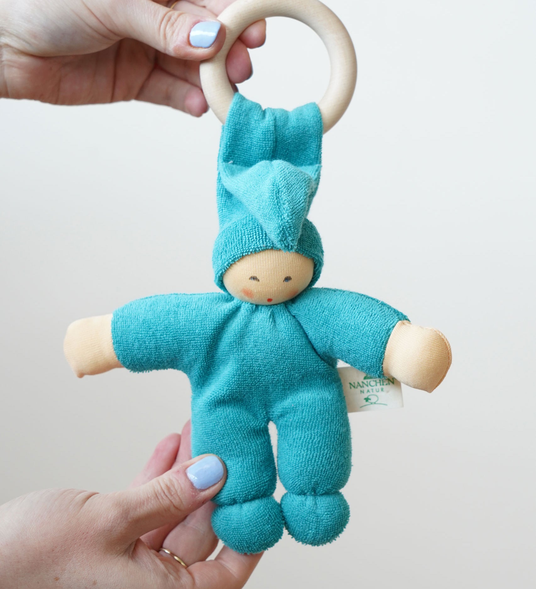 A turquoise coloured Nanchen Pimpel Waldorf Doll Ring Comforter in an adult's hands. 