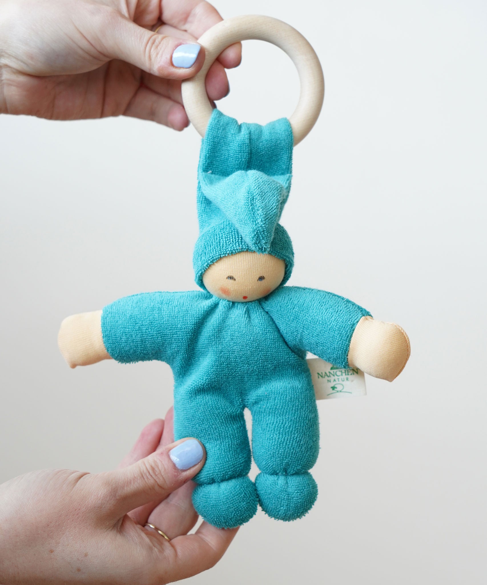 A turquoise coloured Nanchen Pimpel Waldorf Doll Ring Comforter in an adult's hands. 