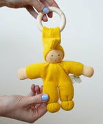 A close up of a yellow Nanchen pimpel doll in an adult's hand.