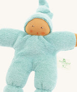 Close-up of the Nanchen Pimpel Waldorf Doll in sage green, showing its soft terry cotton body and sweet hand-painted facial features. The doll wears a pointed hood and has rosy cheeks, with a "Nanchen Natur" tag on its side.